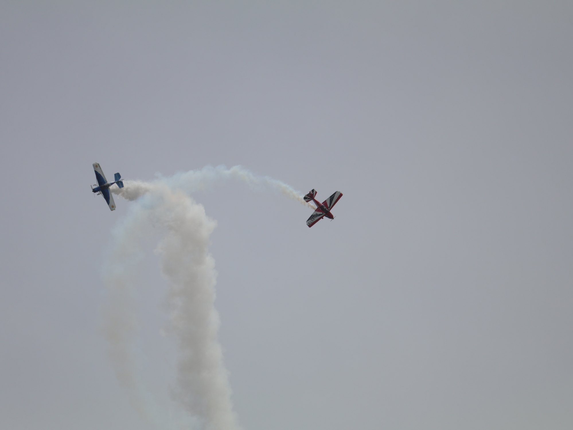 Dos aeronaves acrobaticas cruzandose entre estelas de humo