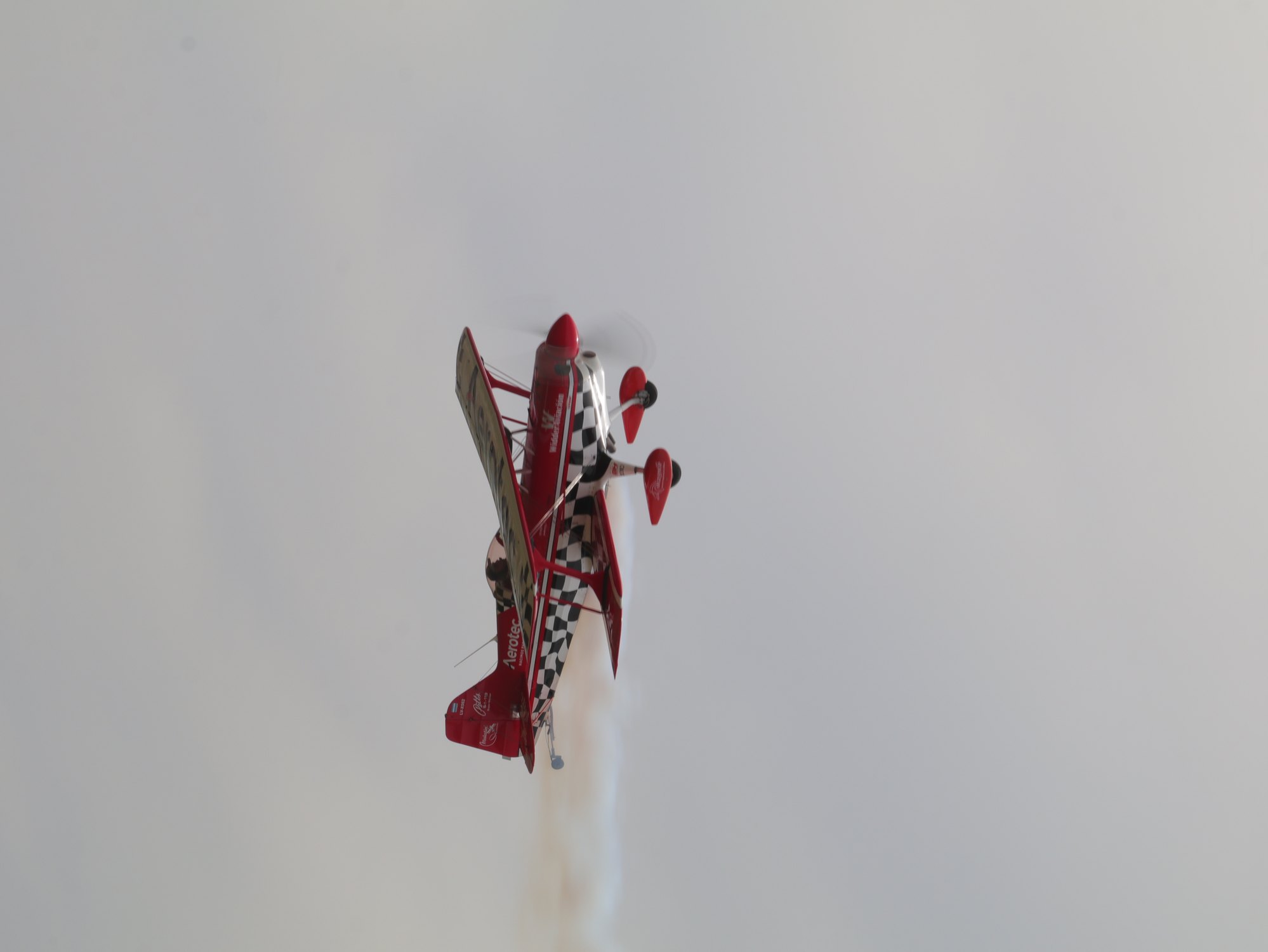 Biplano acrobatico rojo realizando un vuelo invertido